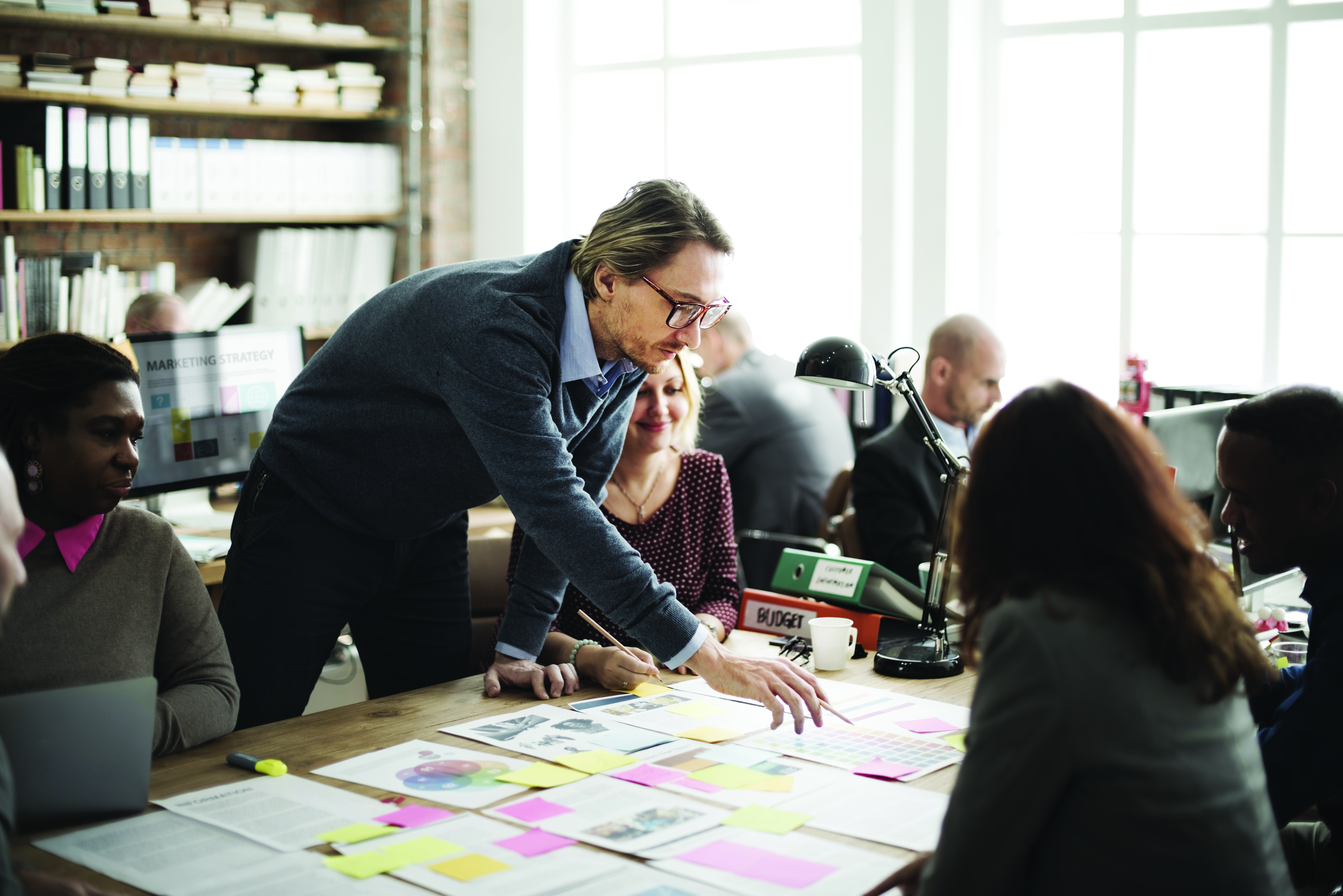 A group of people in a meeting room look over papers for budgets